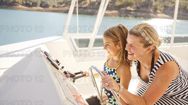 Mother and daughter steering boat on lake