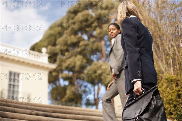 Businesswomen walking up stairs together