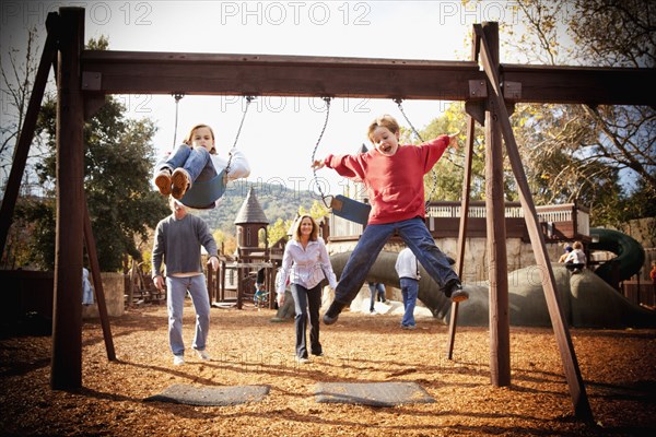 Parents watching children swinging