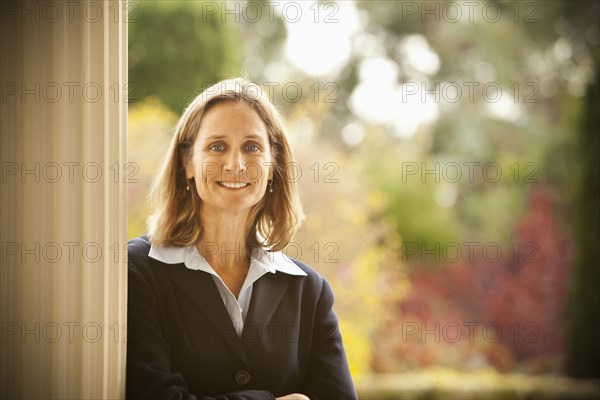 Caucasian businesswoman leaning against post