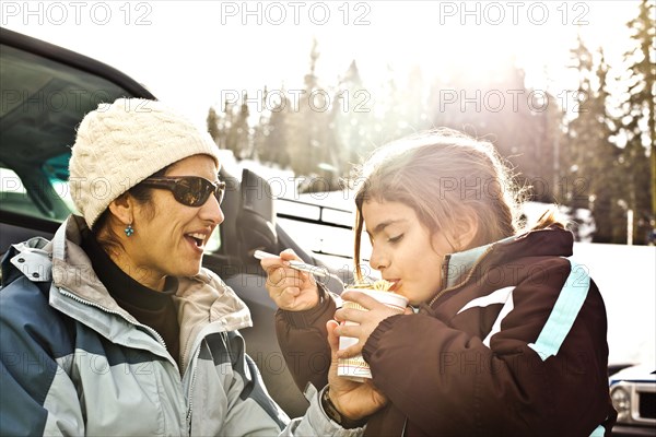 Mother and daughter eating lunch in snow