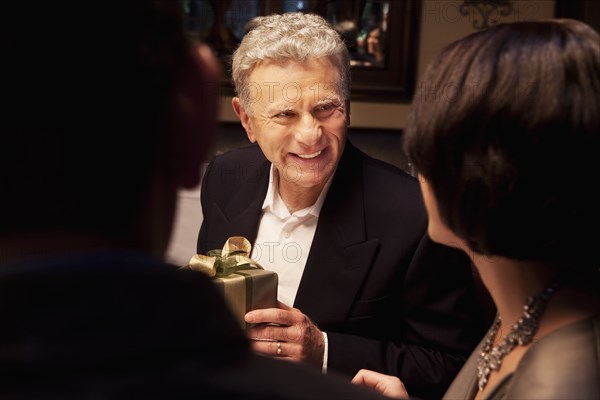 Caucasian man giving woman gift in restaurant