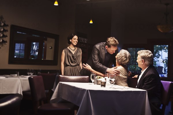 Couple greeting friends in restaurant