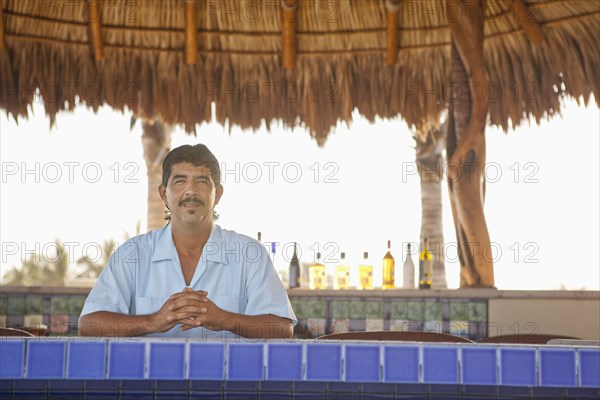 Hispanic bartender standing behind bar