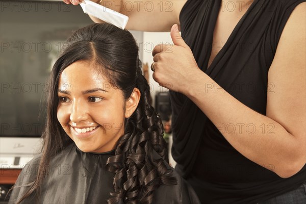 Hispanic woman having hair styled in salon