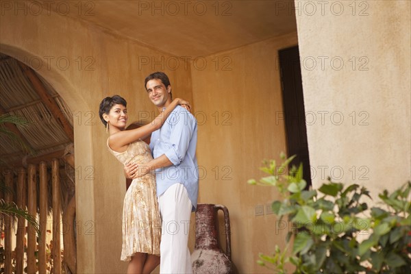 Hispanic couple hugging on front stoop