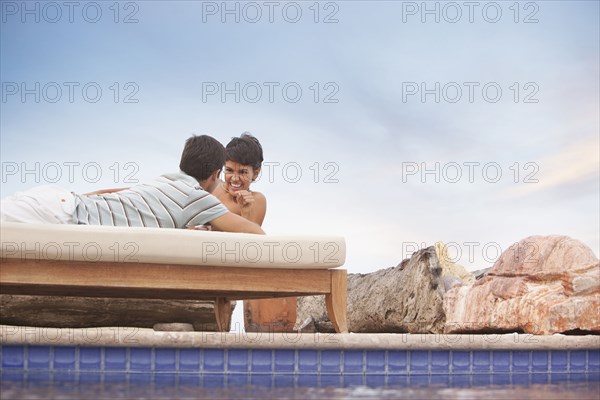 Hispanic couple relaxing at poolside