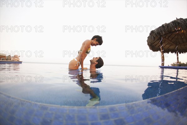 Hispanic couple enjoying swimming pool