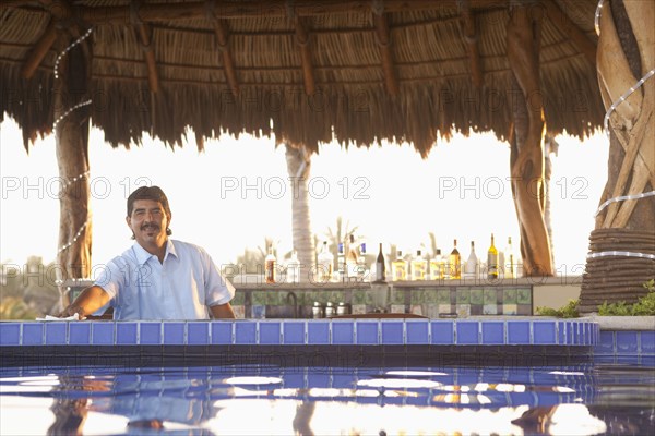 Hispanic bartender working near poolside