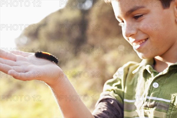 Boy holding caterpillar in his hand