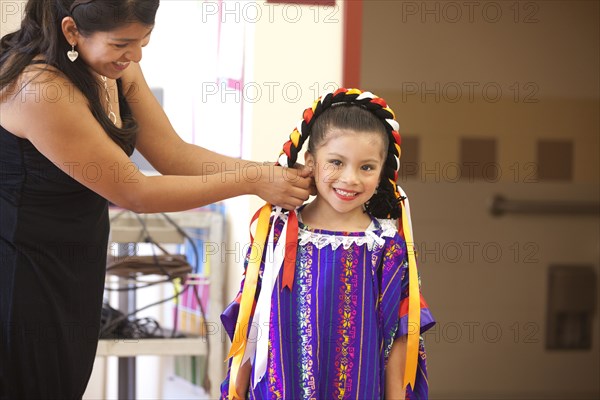 Hispanic mother helping daughter with festive costume