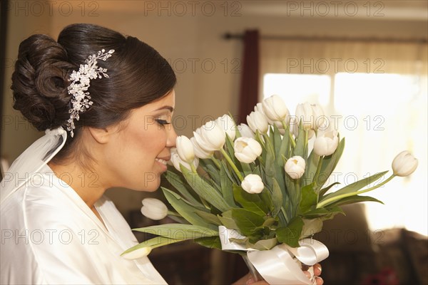 Hispanic bride smelling bouquet