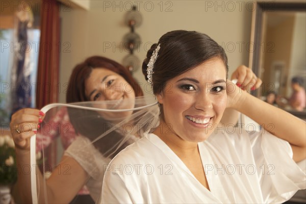 Hispanic bride arranging veil