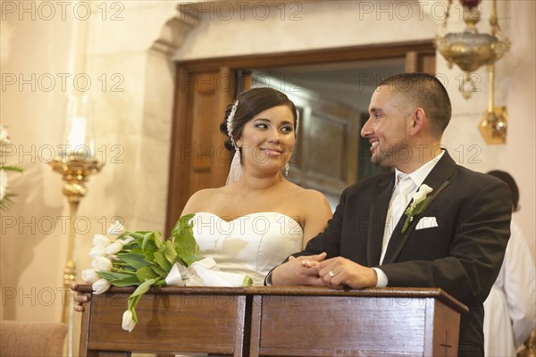 Hispanic bride and groom in wedding ceremony