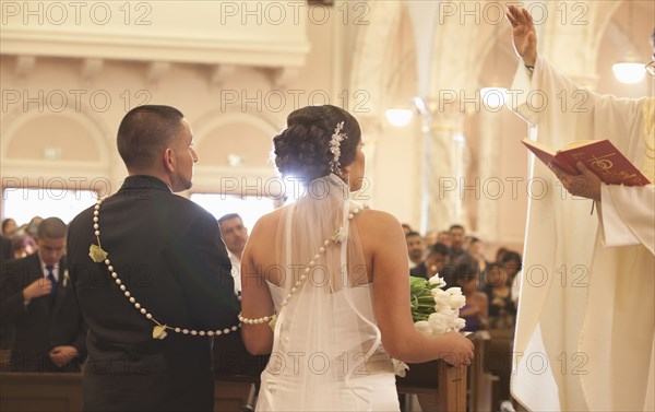 Hispanic bride and groom in wedding ceremony