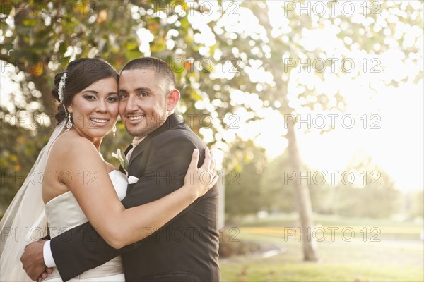 Hispanic bride and groom hugging