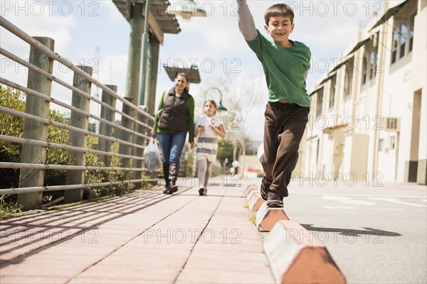 Boy balancing on edge of sidewalk