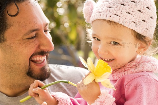Father smiling at daughter with flower