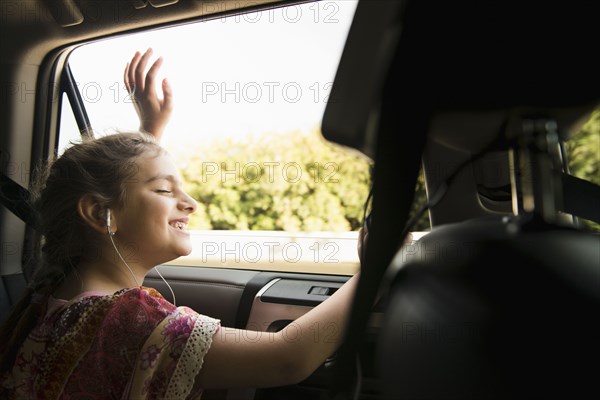 Mixed race girl listening to headphones in car