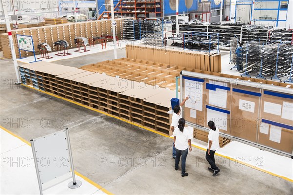 Workers reading bulletin board in manufacturing plant