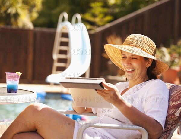 Hispanic woman using digital tablet by pool