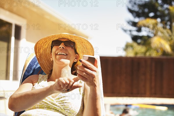 Hispanic woman using cell phone by pool