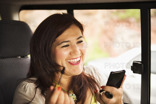 Hispanic woman using cell phone in car