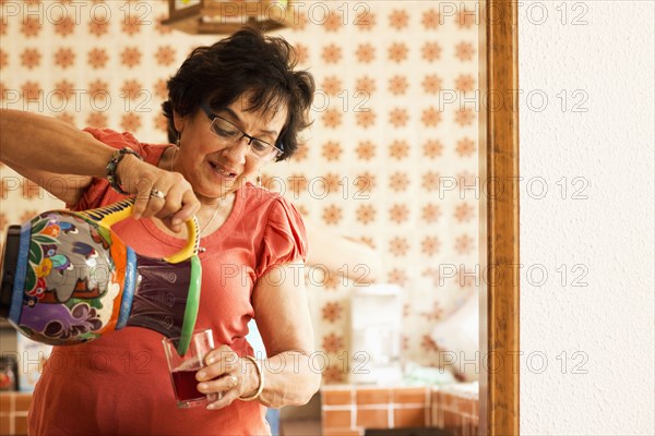 Woman pouring glass of juice in kitchen