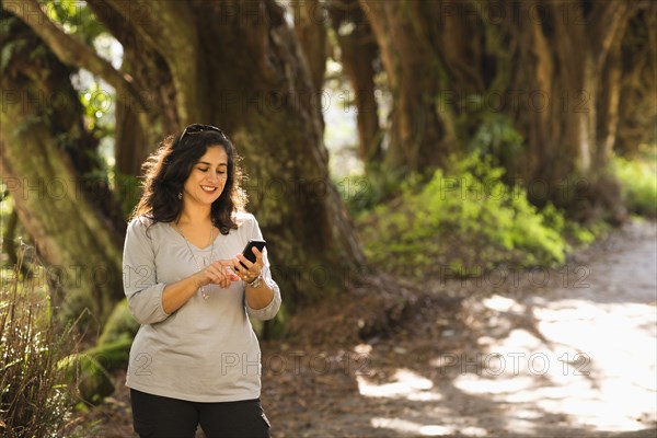 Hispanic woman using cell phone outdoors