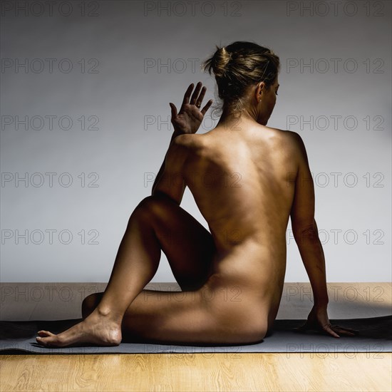 Nude Caucasian woman practicing yoga in studio