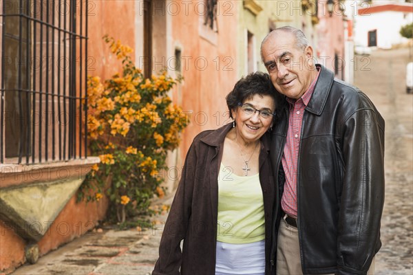 Older Hispanic couple walking on village street