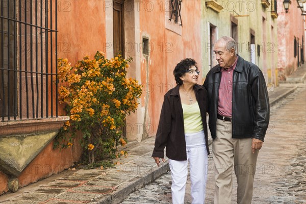 Older Hispanic couple walking on village street