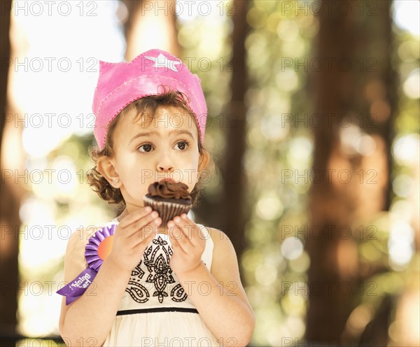 Hispanic girl eating cupcake outdoors