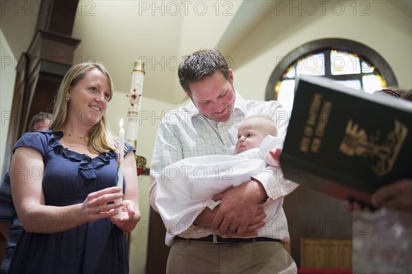 Caucasian parents having baby baptized in church