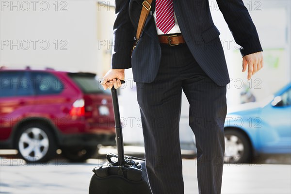 Hispanic businessman rolling luggage