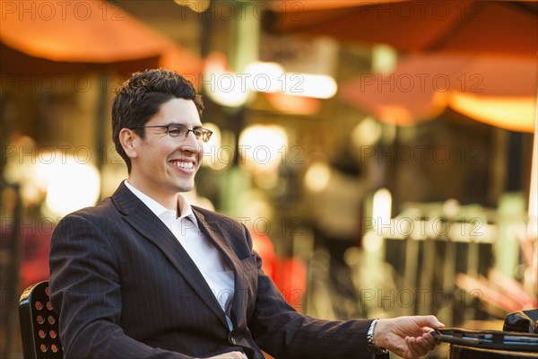 Hispanic businessman smiling at cafe