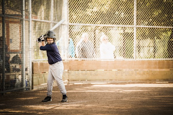 Mixed race boy playing baseball in field