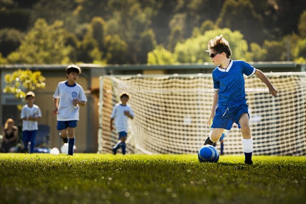 Caucasian boy playing soccer on pitch