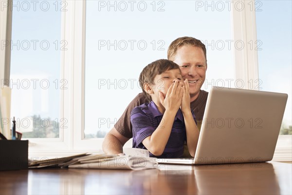 Father and son using laptop at desk