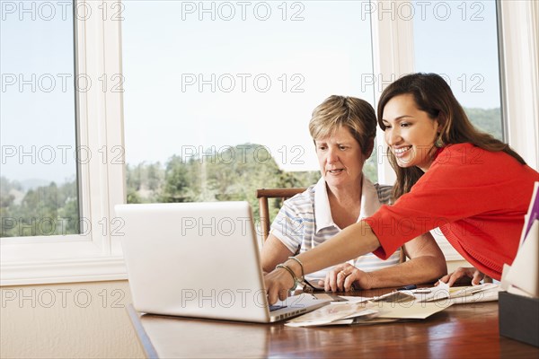 Mother and daughter using laptop at desk