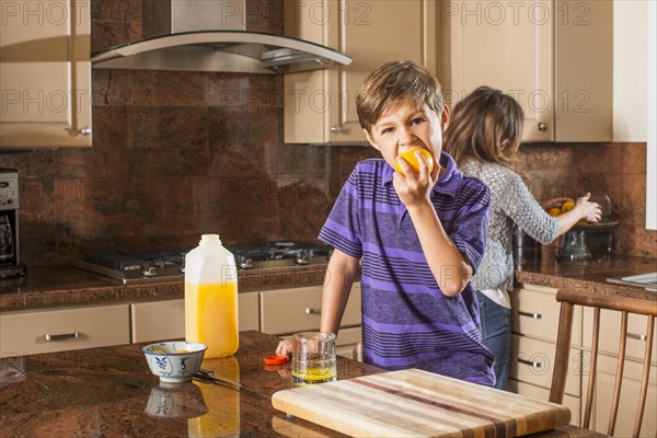 Boy eating fruit in kitchen