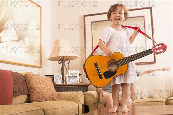 Hispanic girl playing guitar in living room