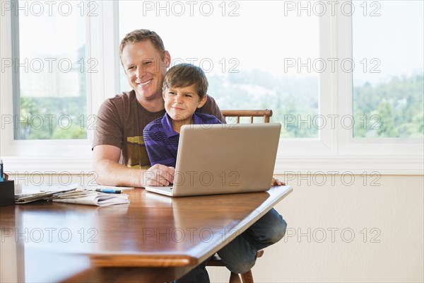 Father and son using laptop together