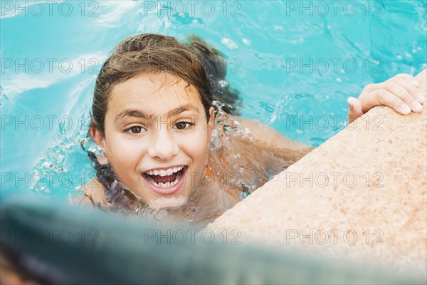 Mixed race girl swimming in pool