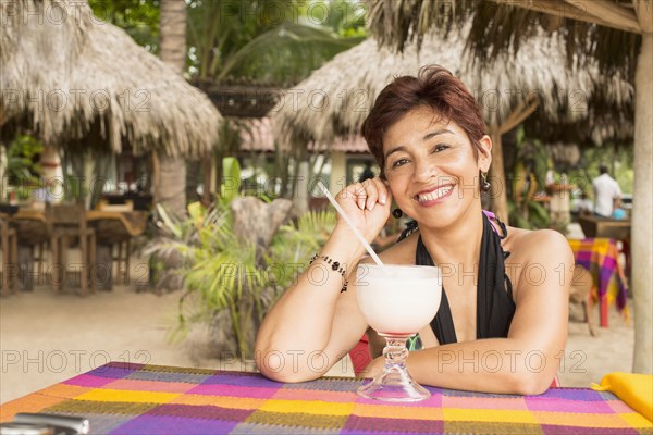 Hispanic woman enjoying tropical drink at resort