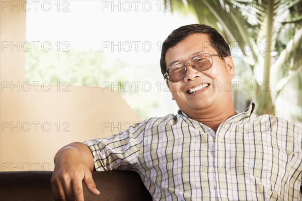 Hispanic man smiling on sofa