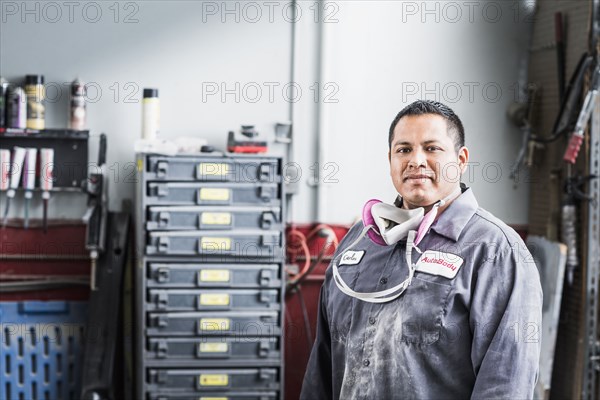Hispanic mechanic standing in auto shop