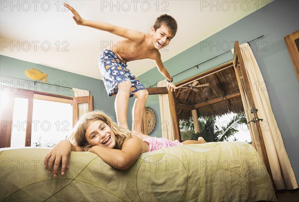 Mixed race children playing on bed