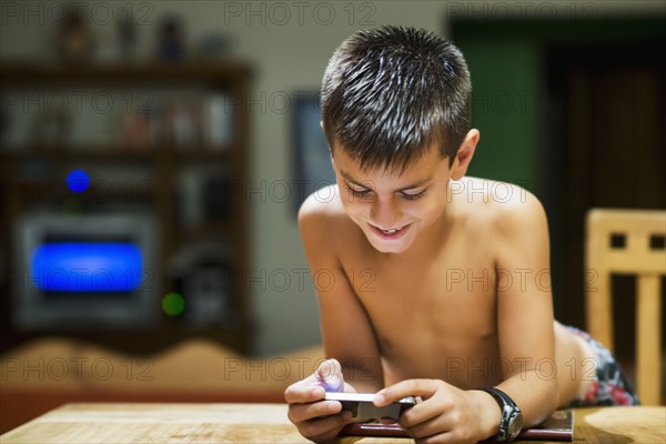 Hispanic boy using cell phone at table