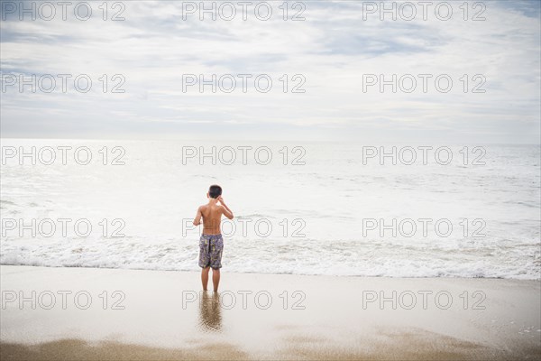 Hispanic boy standing in surf at beach
